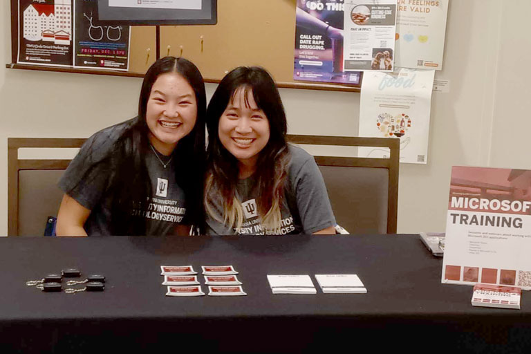 Two students at an information table for Microsoft Training